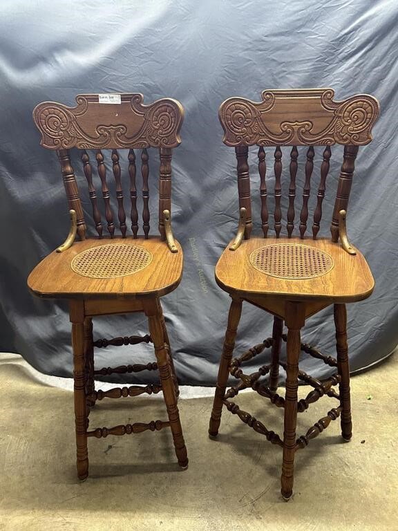 Oak cane seated swivel bar stool pair with carved