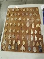 APPROXIMATELY (65) ARROW HEADS ON A PLANK OF WOOD