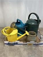 Metal and plastic watering cans, pottery vase