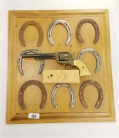 Wooden panel with horseshoes replica revolver