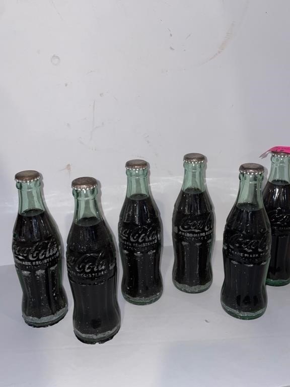 Six full Coca-Cola collectors glass bottles