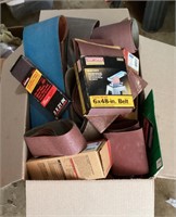 Box of sandpaper with new and used sanding belts