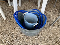 metal tub of garden hoses and blue buckets