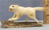 Fossilized ivory carving of a running wolf mounted