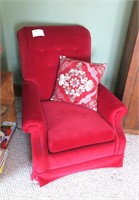 Red velour chair with throw pillow