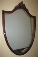 Shield shaped wall mirror with carved wood top.