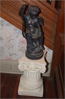 Statue of Cupid sitting on a white pedestal