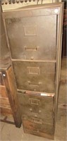 Four drawer metal filing cabinet filled with