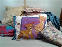 Lot of various sheets blankets pillows and chair