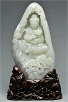 A QING DYNASTY WHITE JADE GUANYIN BOULDER & STAND