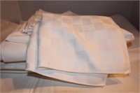 Lot of white checkered table cloths and mats.