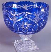 A blue overlay cut glass punchbowl on a clear