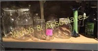 Shelf of glass jars, vases, growlers, steins, etc.