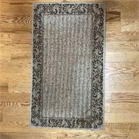 Grey area rug with scrollwork border.