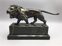 Metal statue of lion on marble base