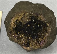 A round purple with gold flecked geode, outside is