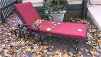 Black iron chaise with a red cushion and has
