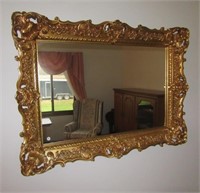 Ornate gold colored plastic framed wall mirror.