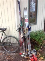 Lot of downhill skis, poles and pair of boots.