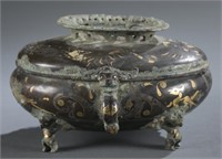 A gold and silver inlaid tripod container.