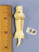 Older, fossilized ivory carving of a sea otter on
