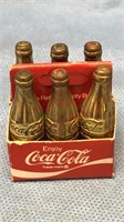 Mini six pack of gold Coca-Cola bottles, one and