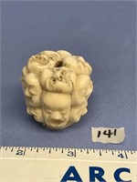 Bone carving 1.5" tall with many faces, signed, ve