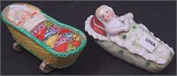 Two baby-in-cradle porcelain figurines: