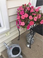 Flowers, watering can, and statue.