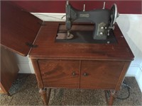 Domestic sewing machine with cabinet.