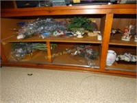 Bottom shelves of greenery, figurines, glassware