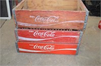 Three red wooden Coca Cola crates
