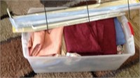 Large tote of linens with curtain rods