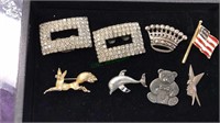 Eight Silvertone brooches , shoe clips ,