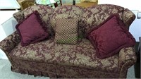 Burgundy and gold sofa with three extra pillows