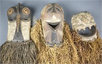 Group of three African masks with raffia.