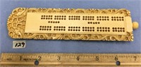 7.5" ivory cribbage board, ornately carved with a