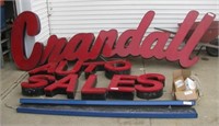 Large neon Crandall Auto Sales sign with