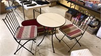 Iron patio table and two folding chairs, table