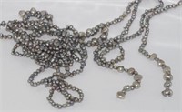 Two silver coloured lariat style sets of pearls