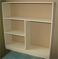 Painted wood display shelf with four sections.