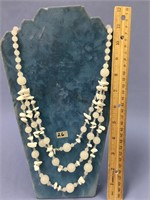 A 3 strand necklace with opaque white beads with w