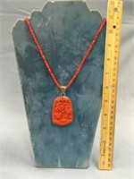 Stone carving, possibly cinnabar, on a red coral b