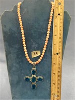 Blue stone cross pendant on a coral bead necklace