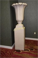 A pair of large urn planters on pedestal bases.