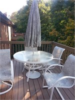 Glass top patio set with four chairs and umbrella