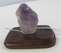 Large amethyst crystal on wood stand.