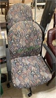 Two floral pattern office chairs, on caster