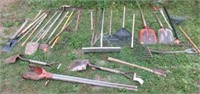 Large collection of yard tools including rakes,