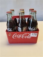 Various Coca Cola Bottles in Plastic Carrier